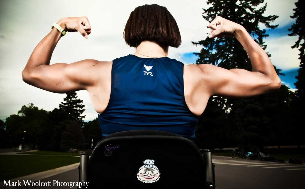 Back view of Tricia Downing flexing while sitting in a chair